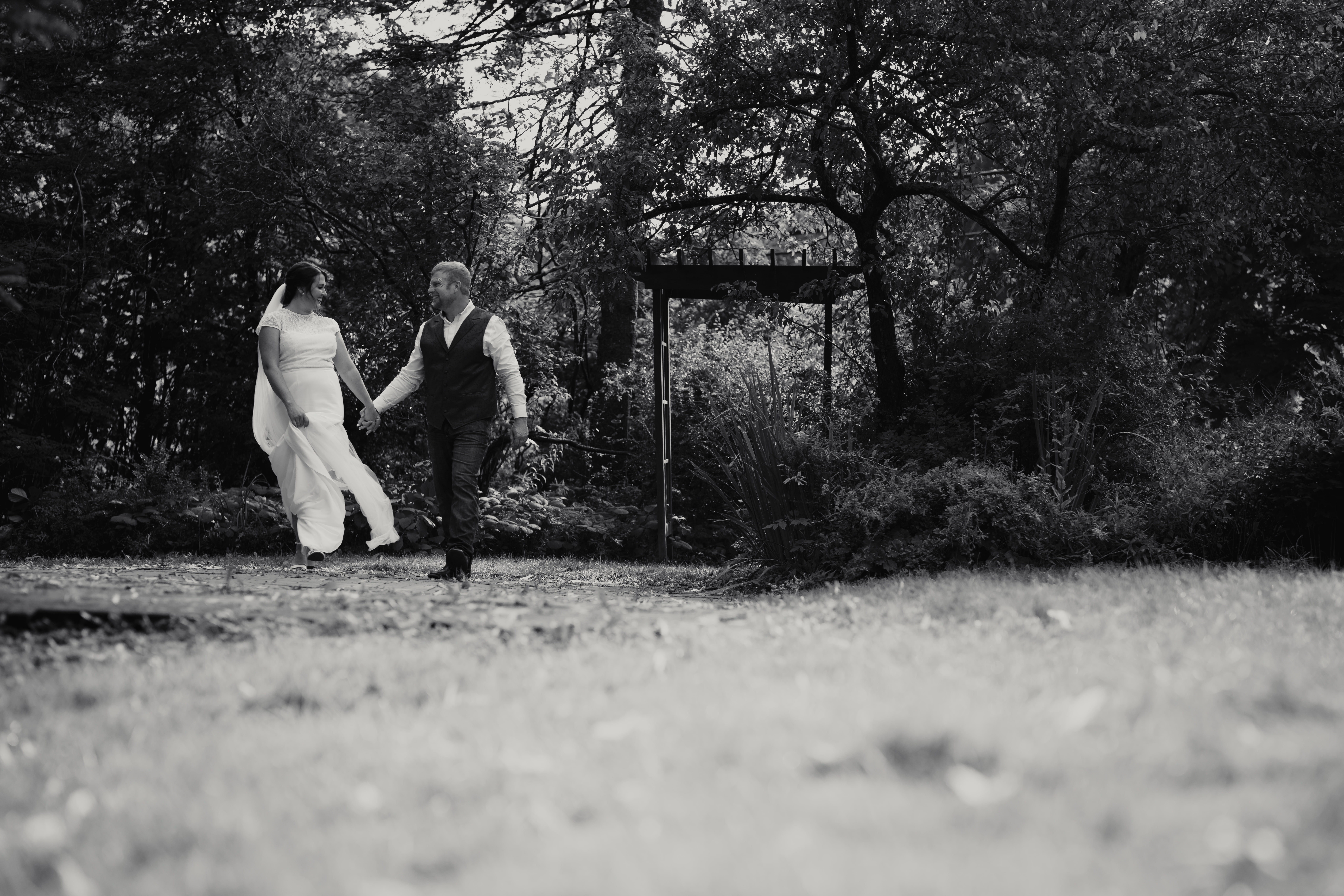 In New Brunswick, a couple walks hand in hand through a black and white garden, capturing the timeless elegance of their wedding day