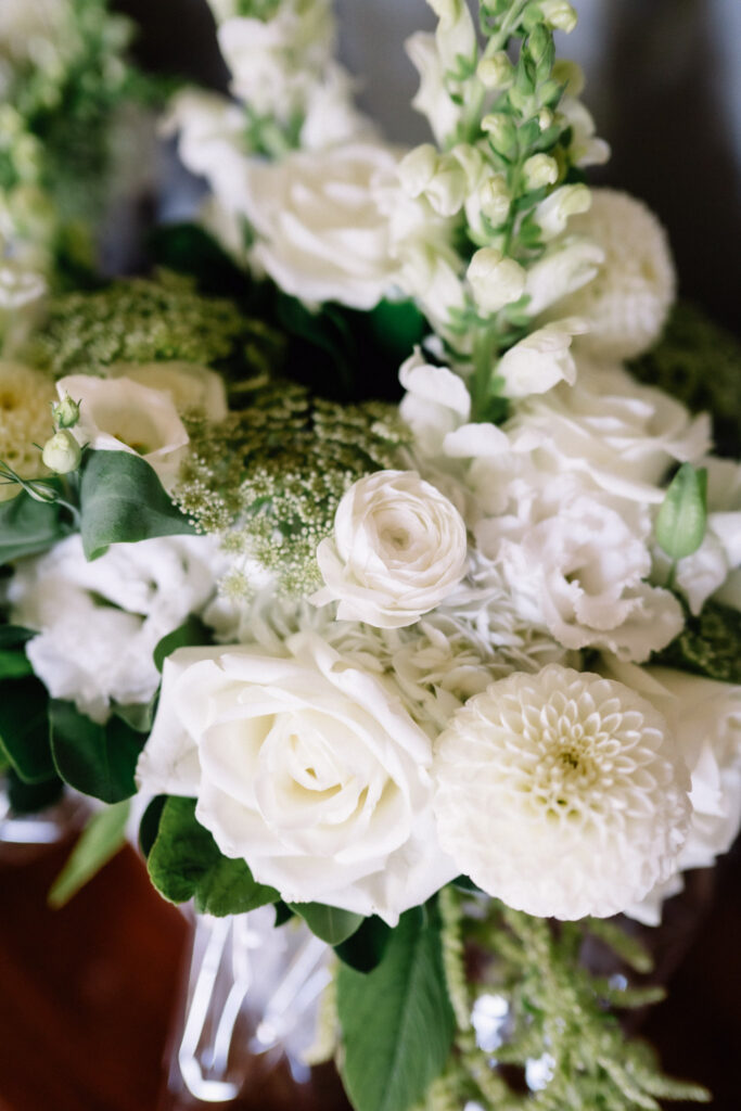 Close-up of Ainsley's bouquet of white roses, dahlias and snapdragons with soft greenery