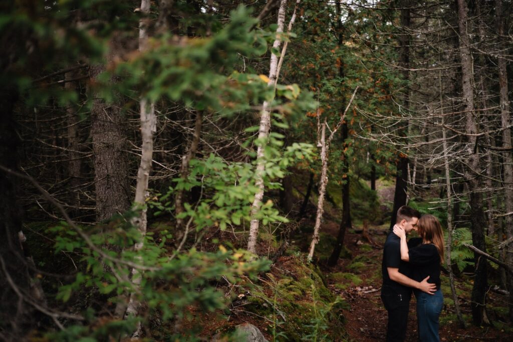 Alexandre and Briar embracing on a forest trail among tall trees at Rockwood Park, Saint John NB